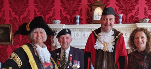 Four people in ceremonial attire in front of ornate fireplace