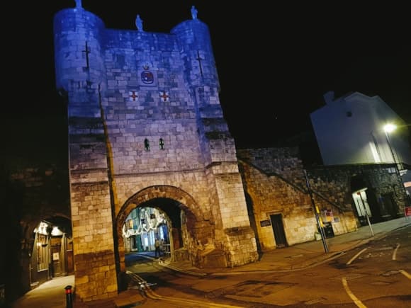Illuminated medieval stone gatehouse with archway at night