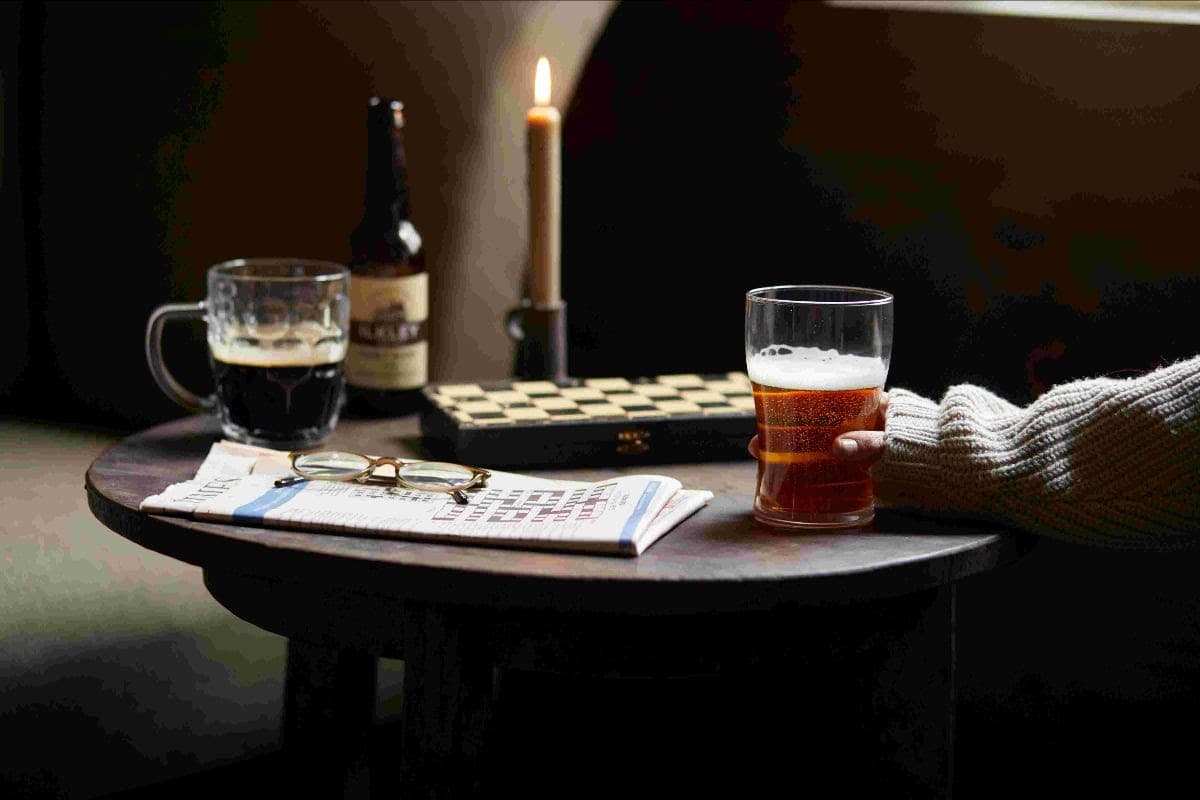 Cozy pub scene with beer, newspaper, and candlelight