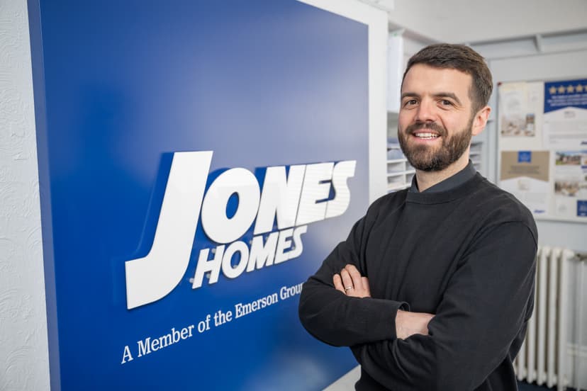 Person standing with arms crossed by Jones Homes sign