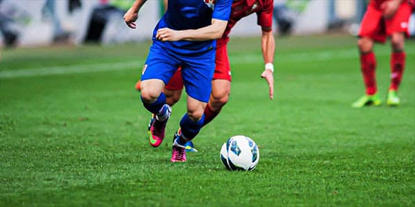 Football match in progress on green field, players in action
