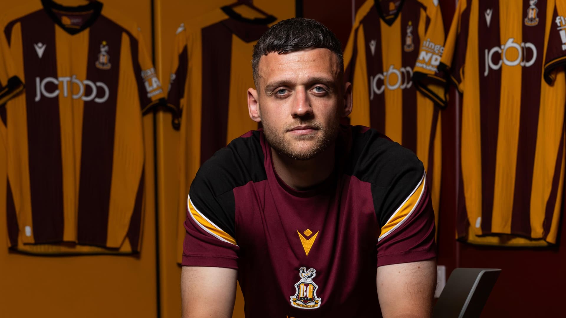 Man in Bradford City football kit surrounded by team shirts
