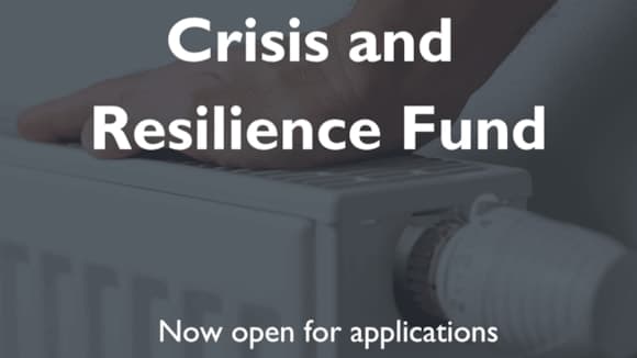 A hand rests on a radiator, with text promoting the Crisis and Resilience Fund for financial assistance in Yorkshire.