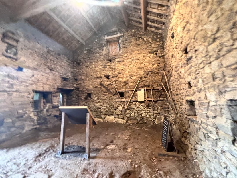 Rustic stone barn interior with wooden beams and display boards