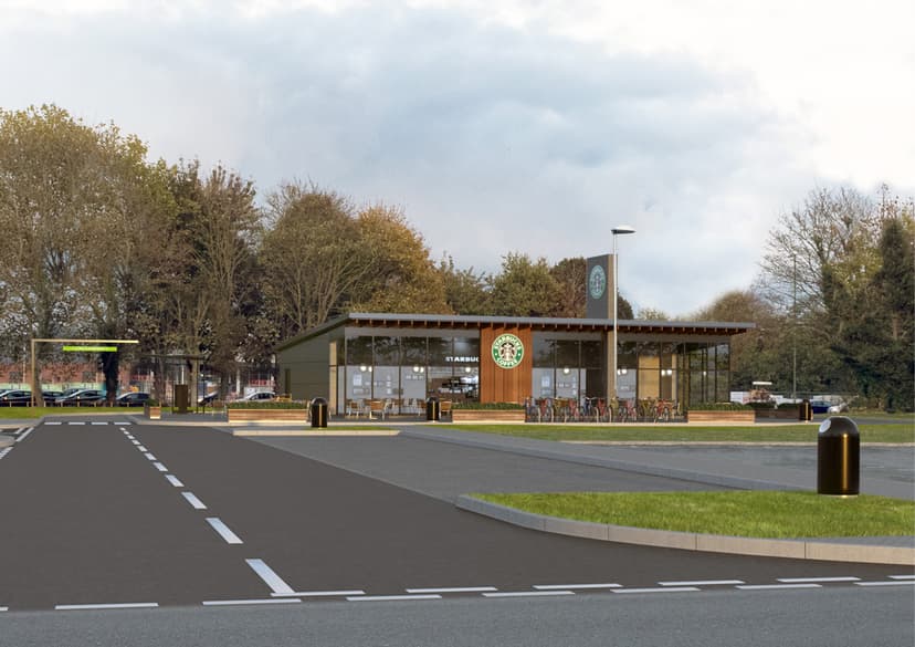 Modern drive-thru building with large windows, surrounded by trees and a paved parking area in Bradford.