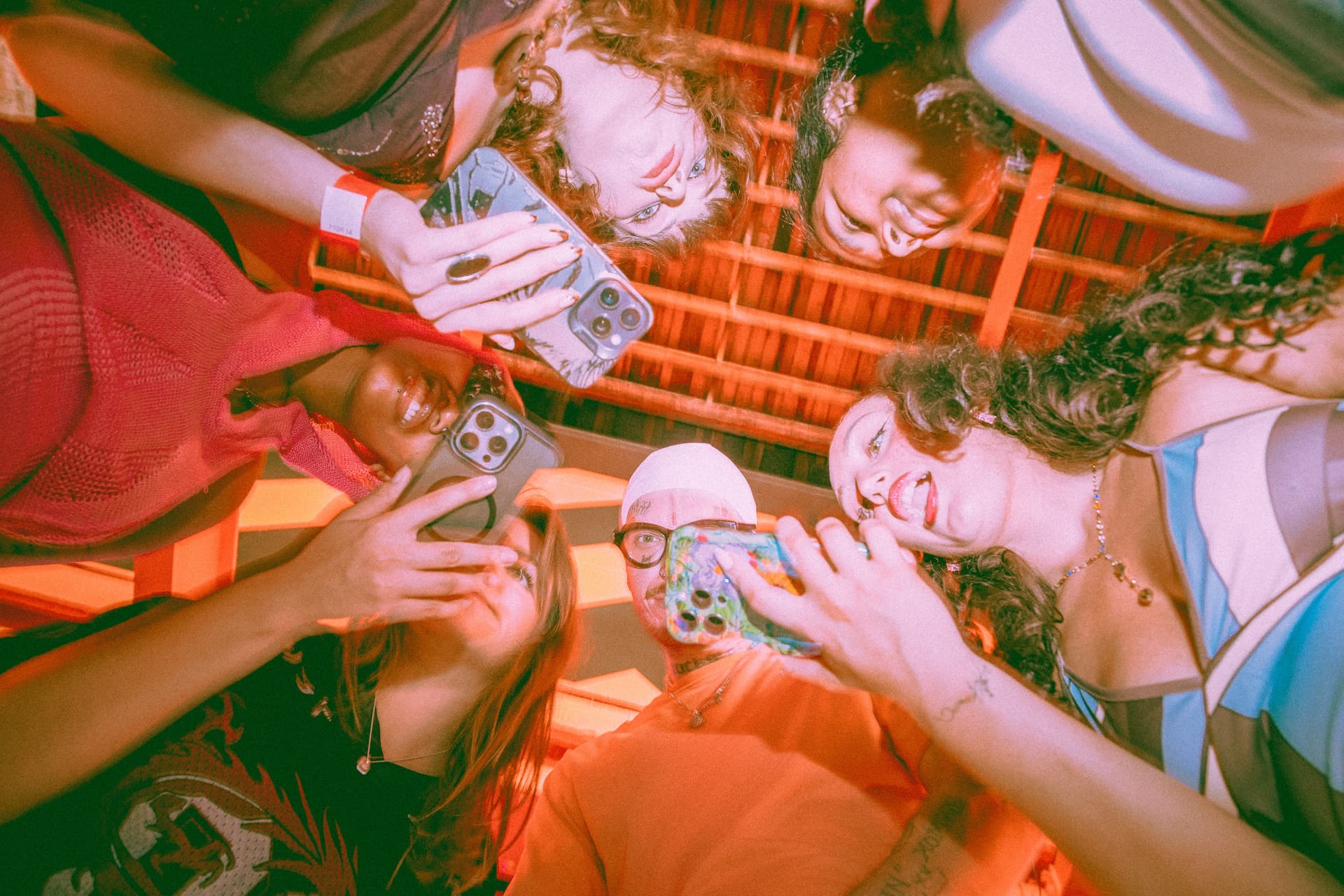 Group of friends in a circle taking photos with smartphones