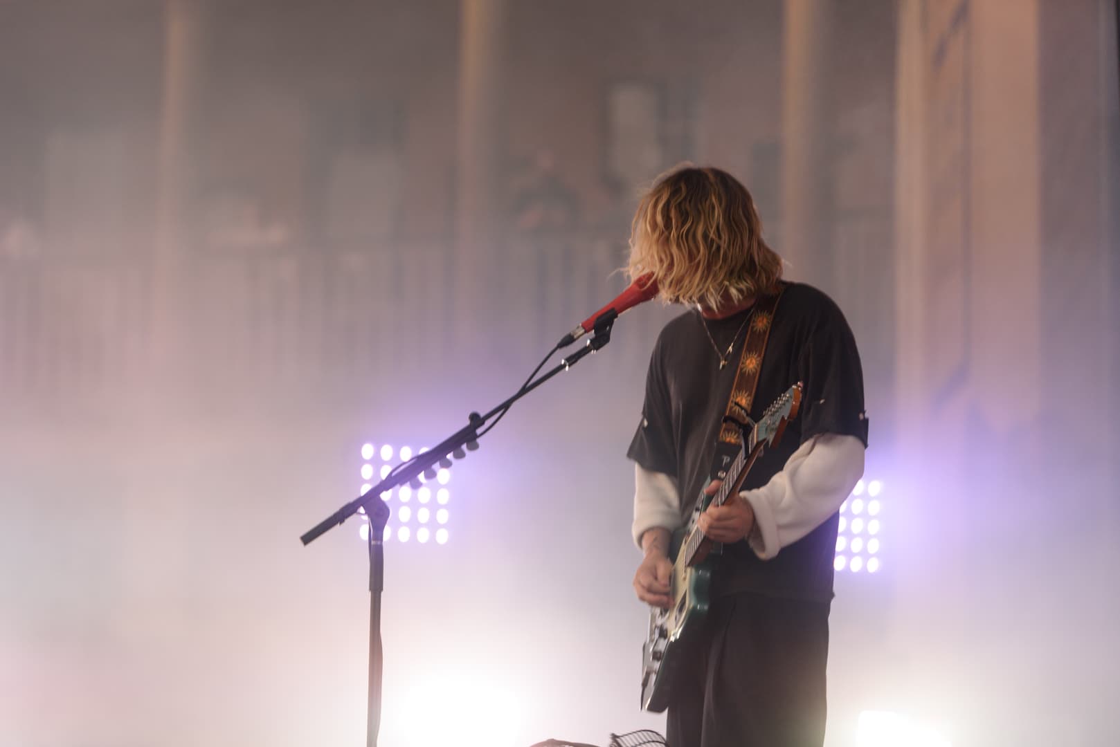 Musician performing on stage with colorful lights and fog