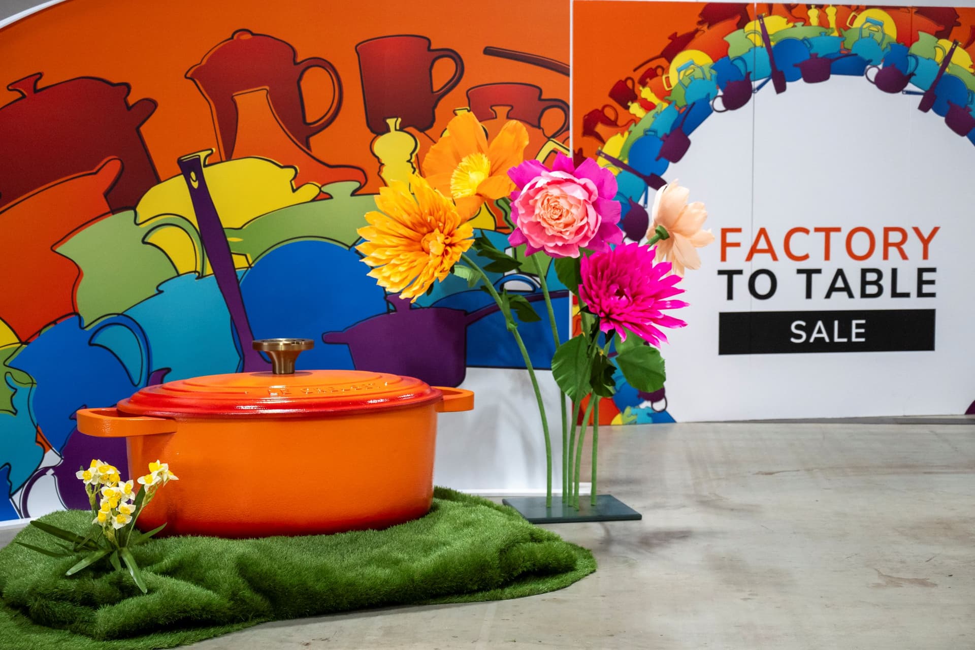 Colourful cookware display with vibrant flowers and sale sign