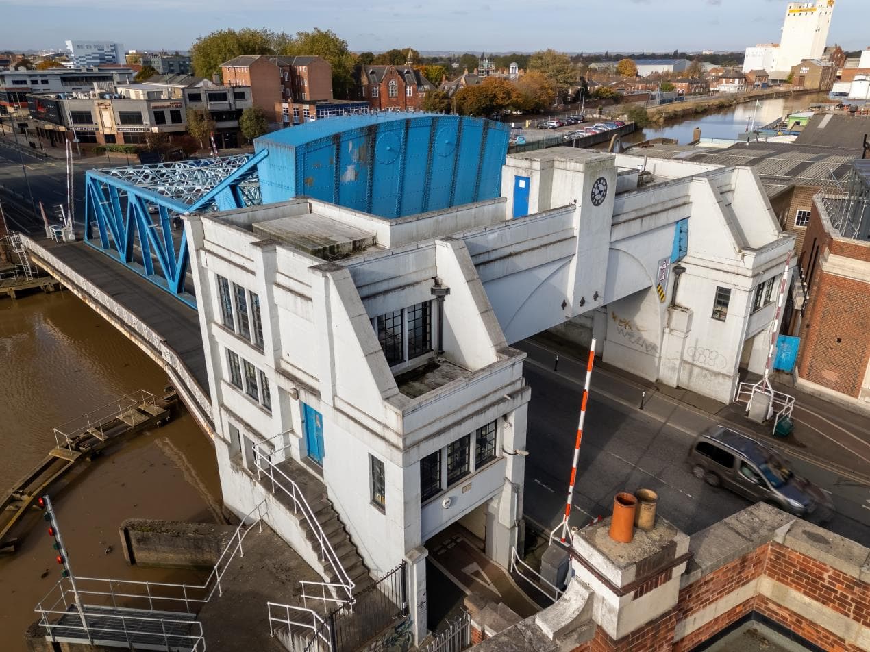 North Bridge in Yorkshire, featuring blue metalwork and white architecture, with a river and urban landscape in the background.