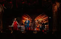 A jazz band performs on stage in a vibrant venue, with colorful lights and an intimate audience enjoying the music.