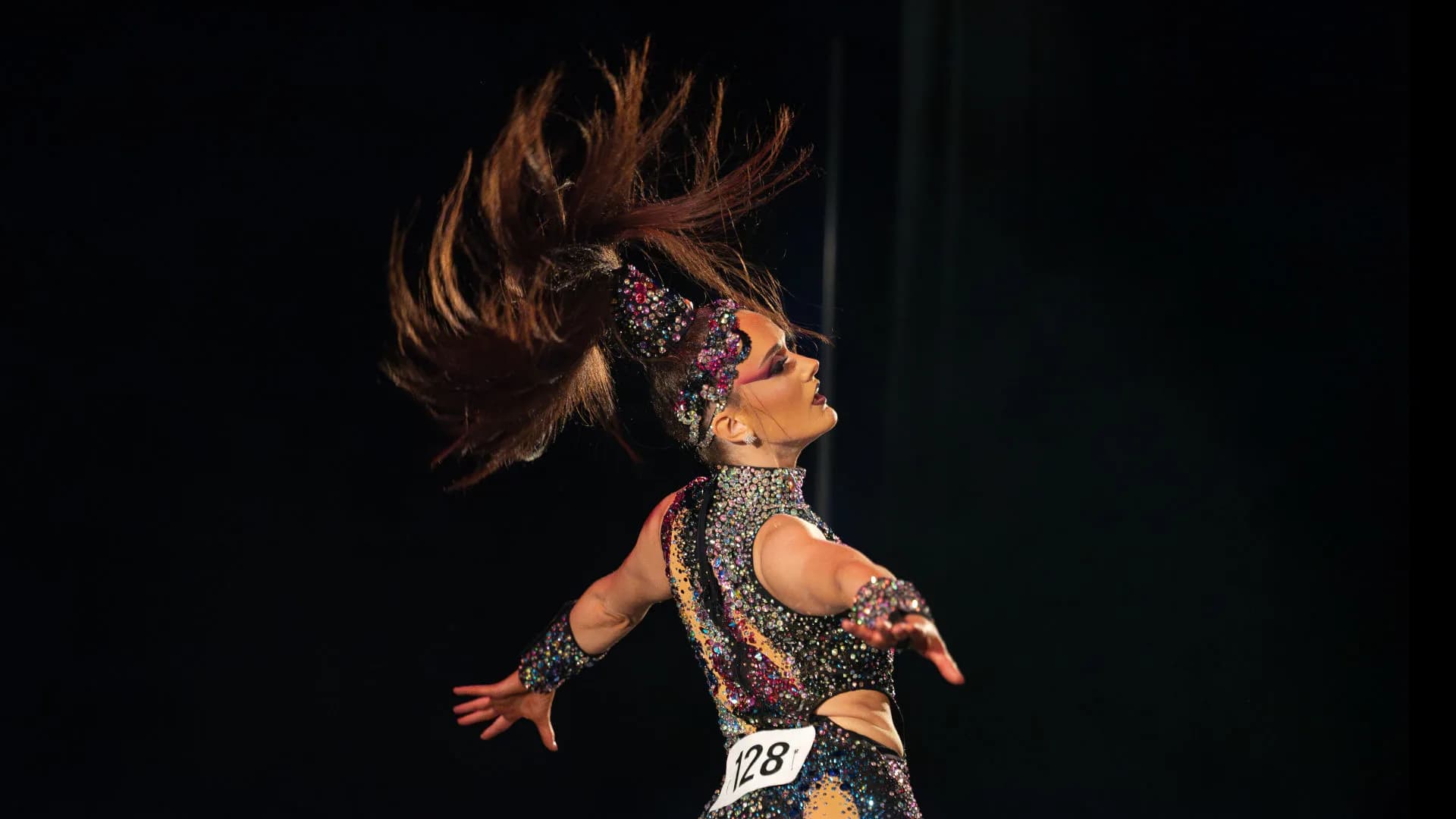 Dancer in sequined costume performing dynamic hair flip