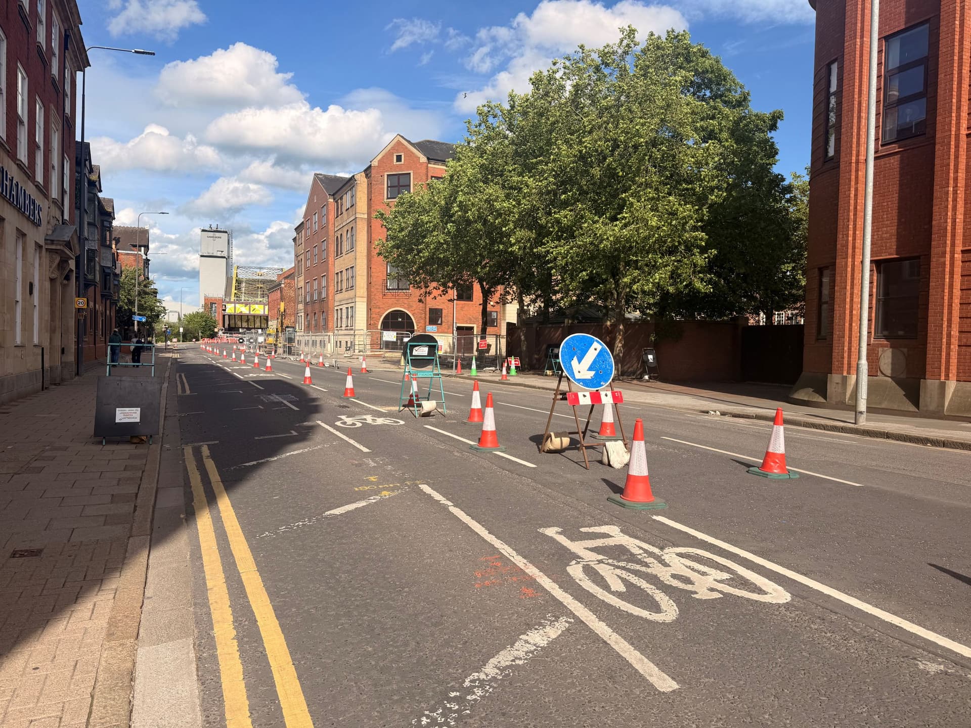Urban street with bike lane, traffic cones, and red brick buildings