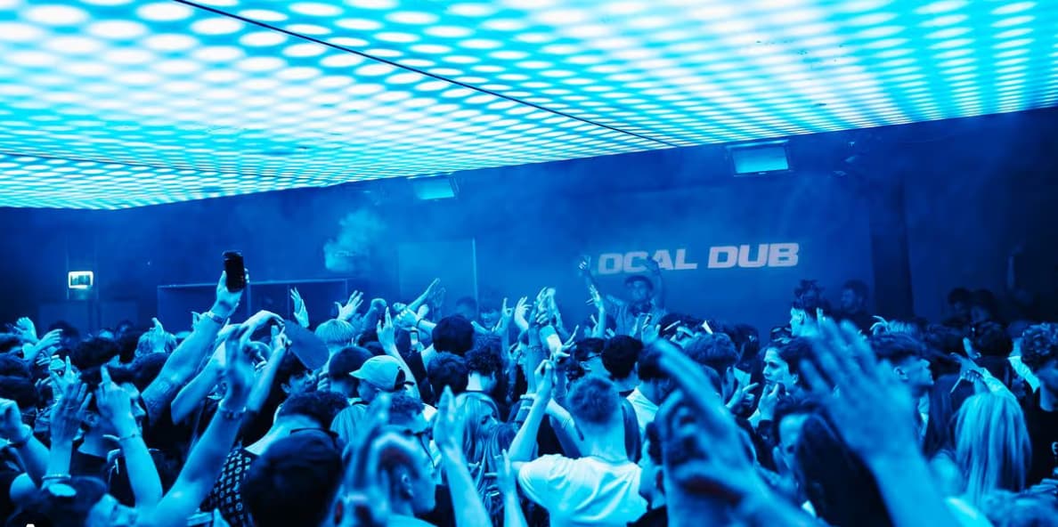 Vibrant nightclub scene with people dancing under blue lights