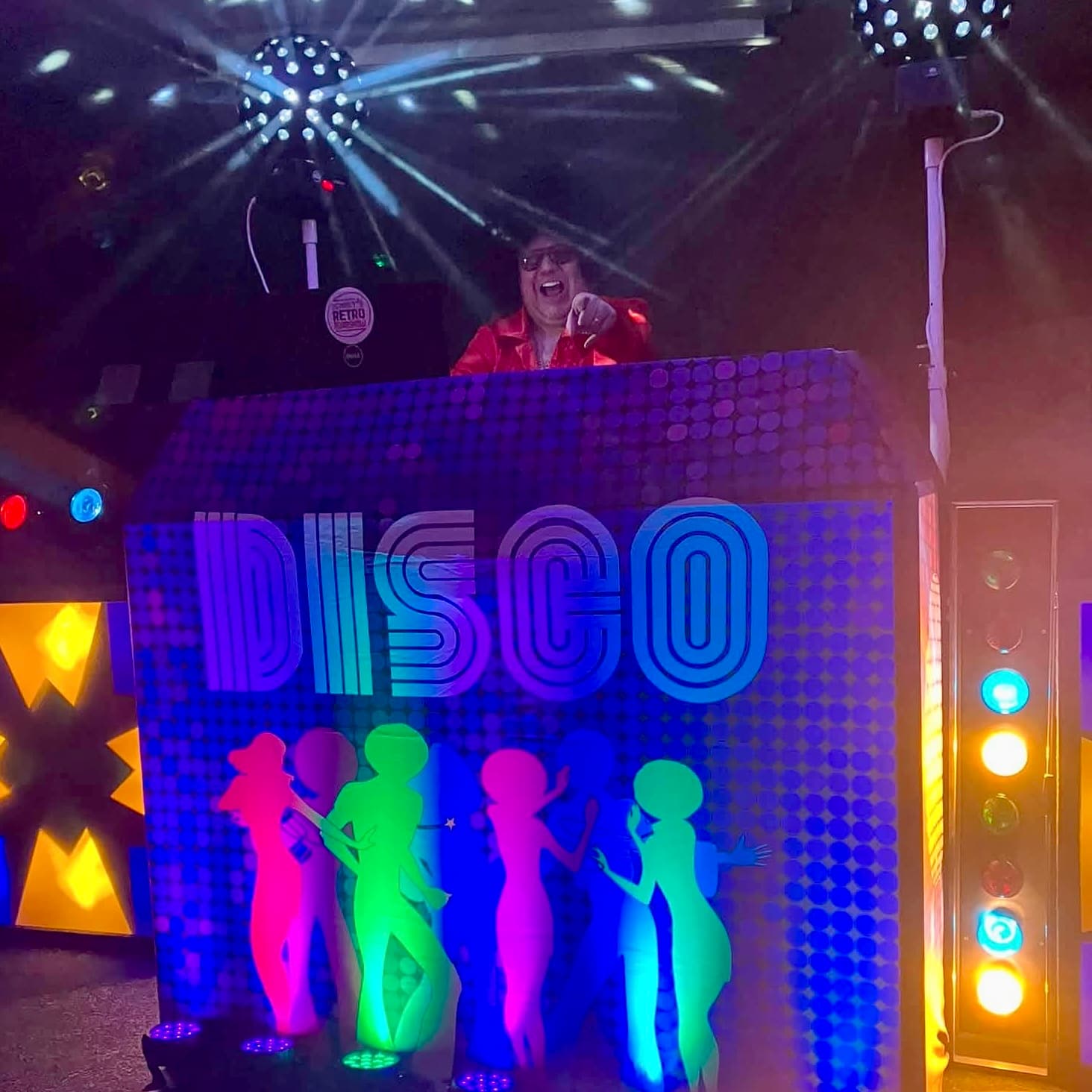 Colourful disco setup with DJ booth and dancing silhouettes