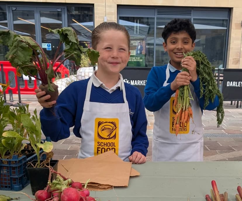 Children holding fresh vegetables at outdoor market stall