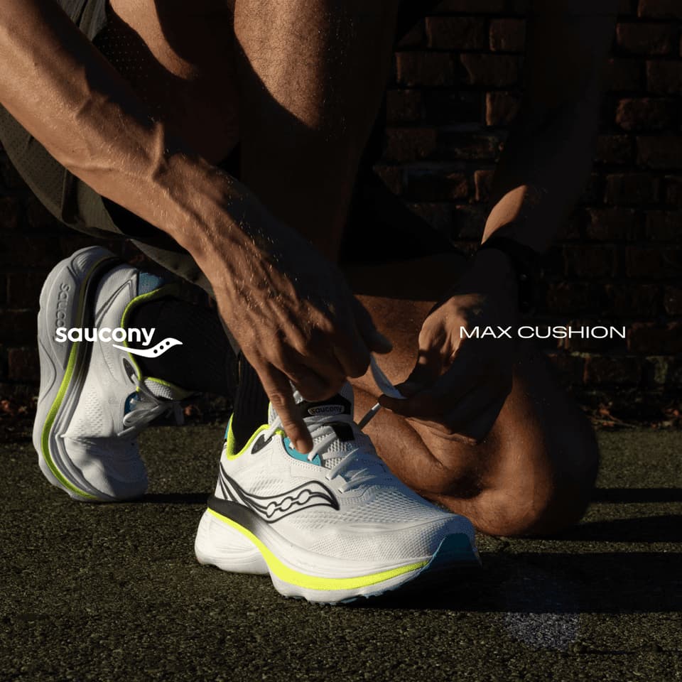 Person tying laces on white running shoes with neon details