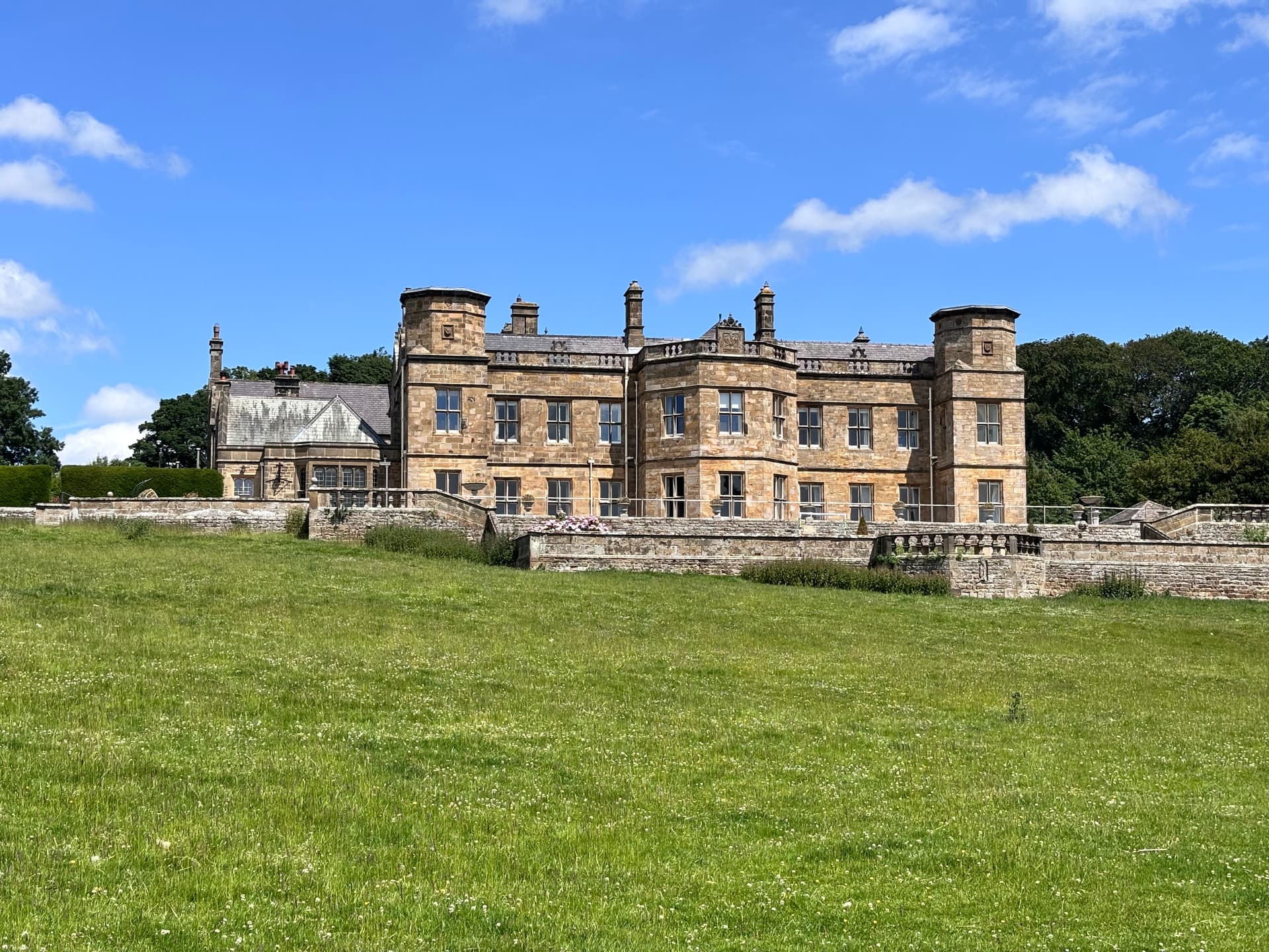 Historic stone manor with turrets in lush green landscape