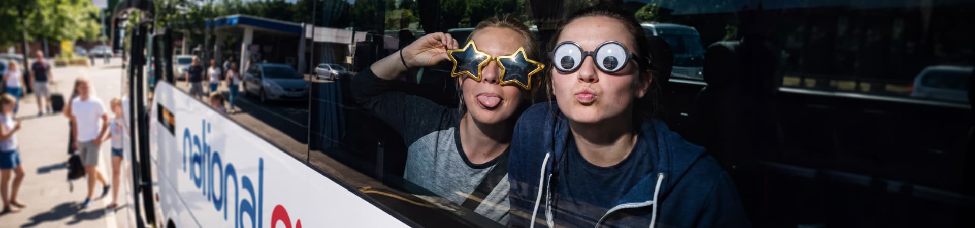Two people making faces with novelty glasses on a bus