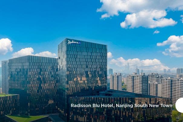 Modern glass hotel building reflecting blue sky in cityscape