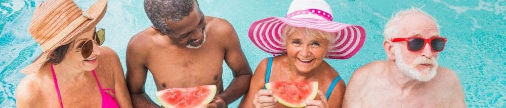 Elderly group in swimwear enjoying watermelon by a pool