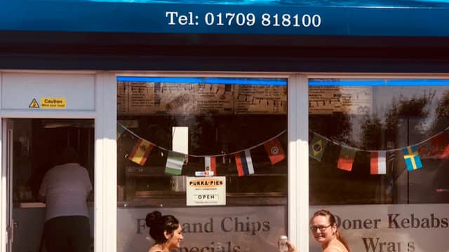 Sign for Oceans Fish Bar with flags, two women dining outside, enjoying food and drinks in Maltby, Yorkshire.