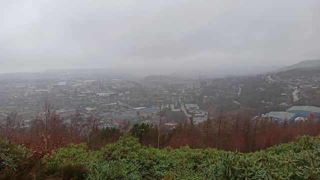 Foggy view of Halifax, Yorkshire, showcasing urban buildings and hills, with trees in the foreground.