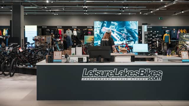 Modern bike shop interior featuring a service counter, bikes on display, and cycling apparel in the background.