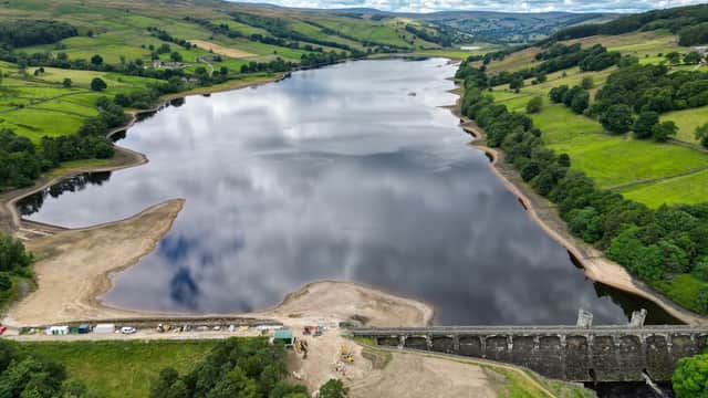 Aerial view of Gouthwaite Reservoir with calm waters, green hills, and a dam structure along the shoreline.