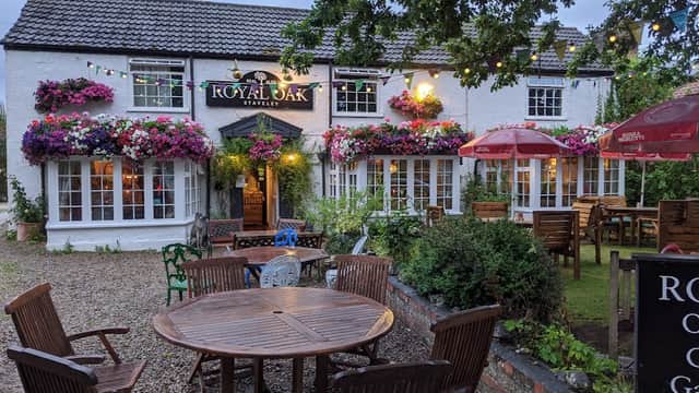 Charming bar with floral displays, outdoor seating, and string lights, set in a cozy Yorkshire village.