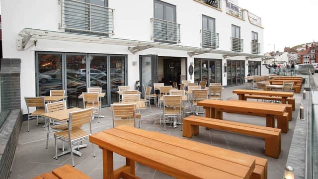 Modern bar exterior with outdoor seating, wooden tables, and large glass windows in Whitby, Yorkshire.