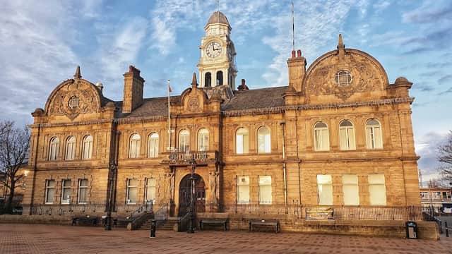Victorian-style town hall with a clock tower, intricate stonework, and a blue sky backdrop in Ossett, Yorkshire.