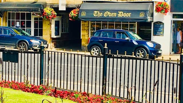 The Oven Door Bakery sign with flower baskets and cars parked outside, set in a picturesque street in Wetherby.