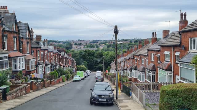 Wigan St Parking in Bradford features terraced houses, parked cars, and a scenic view of greenery in the distance.