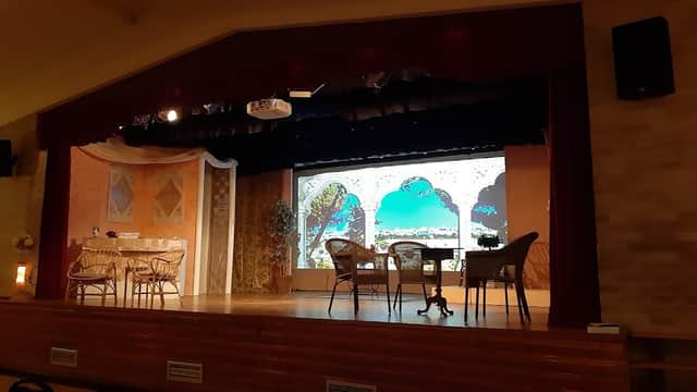 Stage setup at Grenoside Community Centre with chairs, tables, and a decorative backdrop featuring arches and greenery.