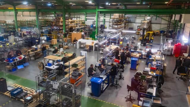 Interior of Debar Ltd ironmongery, featuring workers, shelves of materials, and organized workstations in a spacious warehouse.