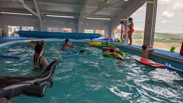 Indoor swimming pool at Ben's School of Swimming with children playing on floats and adults supervising.