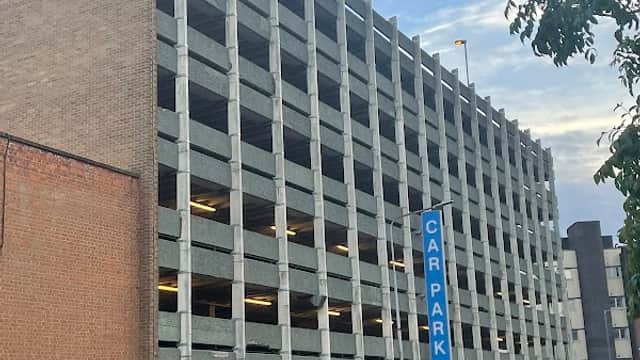 Multi-storey car park with concrete structure, blue "CAR PARK" sign, and a white van parked nearby in Hull, Yorkshire.