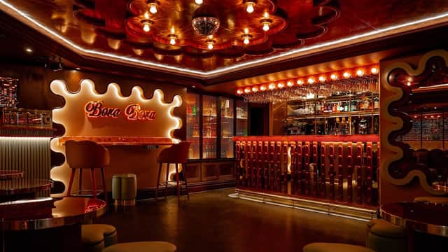 Vibrant nightclub interior with red lighting, stylish bar, and modern seating. Retro decor and a sparkling disco ball.