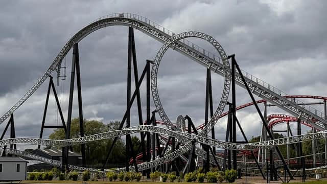 A large roller coaster with black and red tracks, featuring multiple loops, set against a cloudy sky in Kirby Misperton.