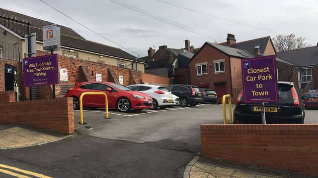 Pay & Display car park with signage, red car, and several parked vehicles in Rotherham, Yorkshire.