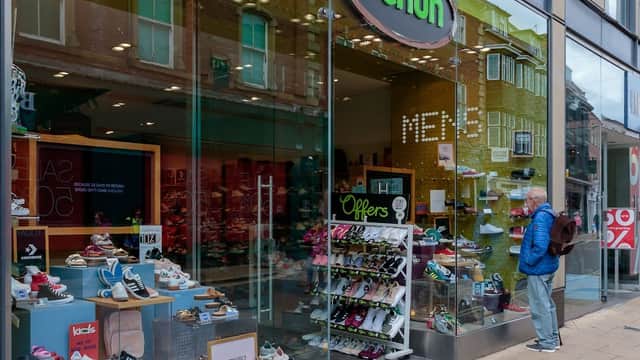 Shoe shop entrance with various shoe displays and a customer browsing outside in Beeston, Yorkshire.