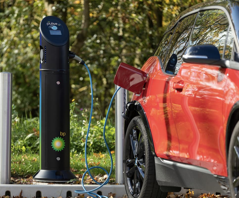 bp pulse charging station with a red electric vehicle plugged in, surrounded by greenery in Harrogate, Yorkshire.