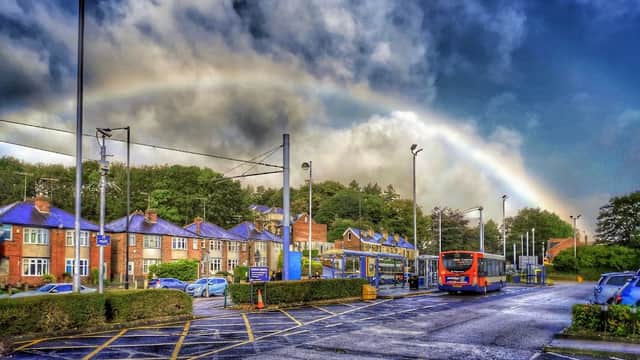 Free parking area at Middlewood Park & Ride, with a rainbow and cloudy sky above, surrounded by greenery and buildings.
