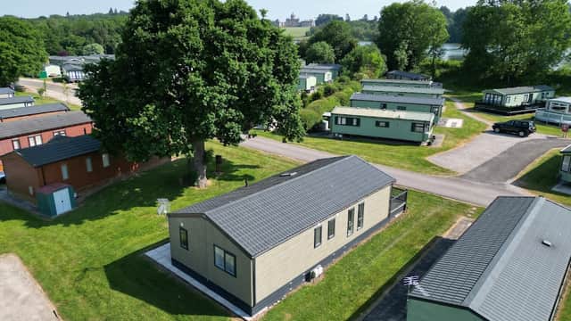 Lakeside holiday park with green caravans, lush trees, and a scenic view of the lake in Coneysthorpe, Yorkshire.