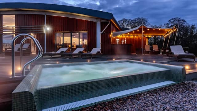 Outdoor spa with bubbling water, lounge chairs, and a modern building under a cloudy sky at The Coniston Hotel.