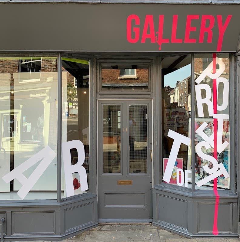 Gallery storefront featuring bold red lettering and large white letters spelling "ART of PROTEST" in the windows.
