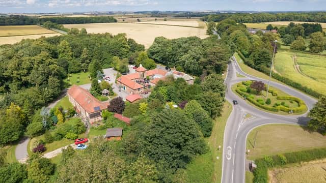 Aerial view of Wolds Village hotel surrounded by greenery, fields, and a circular road in Bainton, Yorkshire.