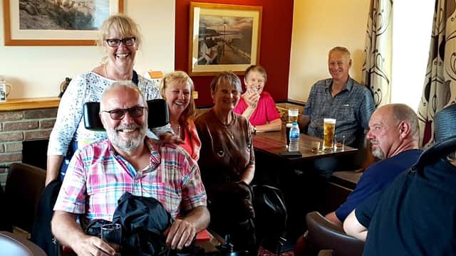 A group of six people smiling inside the White Hart Inn, with drinks on tables and warm lighting.
