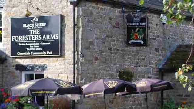 The Foresters Arms restaurant with stone exterior, outdoor seating, and umbrellas in West Scrafton, Yorkshire.