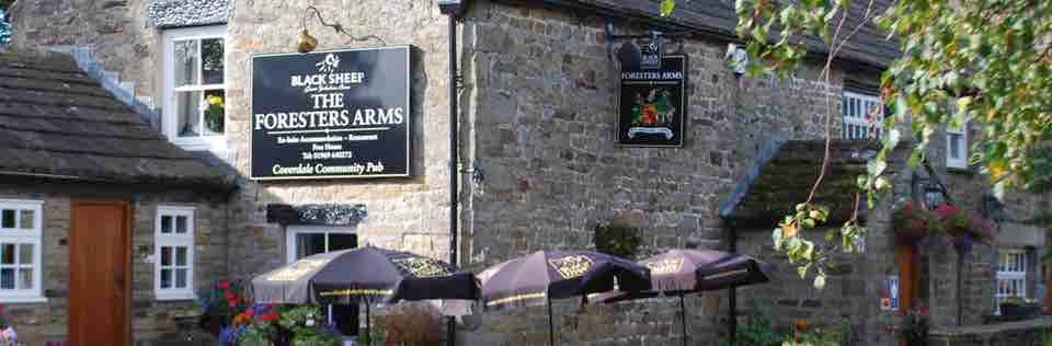 The Foresters Arms restaurant with stone exterior, outdoor seating, and umbrellas in West Scrafton, Yorkshire.